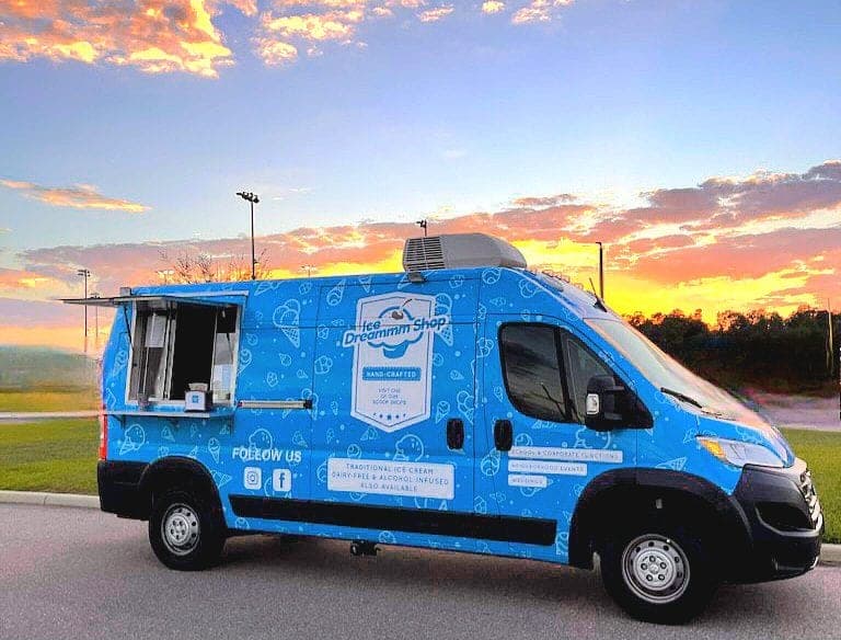 Ice cream truck with its window open under a sunset sky